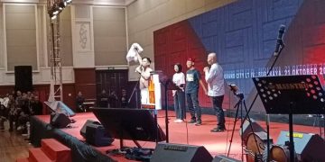 Momen Ketua Dewan Pengelola Daerah (DPD) Rumah Jokowi (RJ) Jatim, Heru Purnomo, saat melepas kemeja Rumah Jokowi di atas panggung