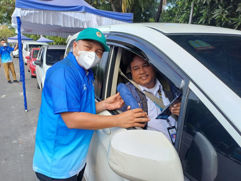 Pegawai Dinas Lingkungan Hidup Kota Tangerang memberikan stiker dan hasil uji emisi kepada pemilik kendaraan roda empat yang lolos uji emisi