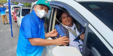 Pegawai Dinas Lingkungan Hidup Kota Tangerang memberikan stiker dan hasil uji emisi kepada pemilik kendaraan roda empat yang lolos uji emisi