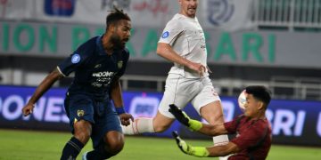 Pesepak bola Persita Tangerang Marios Ogkmpoe (kiri) menendang bola dan berupaya diadang penjaga gawang Persis Solo Muhamad Riyandi (kanan) dalam pertandingan Liga 1 2024/2025 di Stadion Pakansari, Cibinong, Kabupaten Bogor, Jawa Barat, Minggu (8/12/2024). ANTARA FOTO/Arif Firmansyah